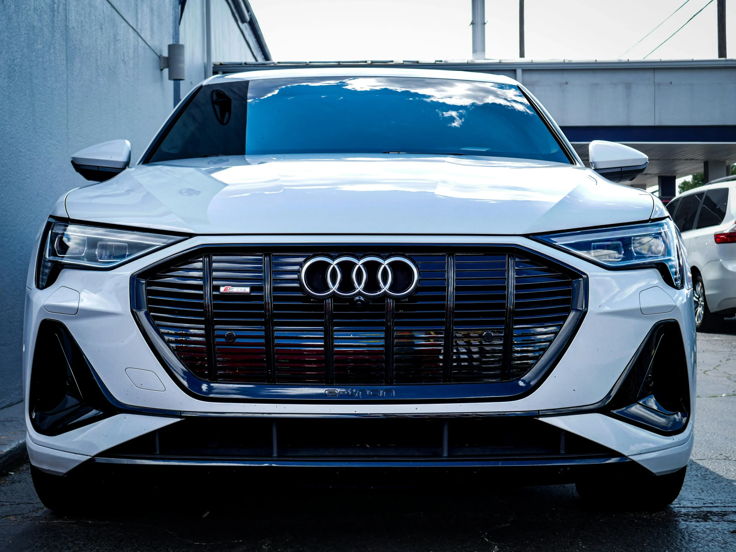 2025 Audi Q6 E-Tron front view showcasing its sleek design, distinctive black grille with Audi logo, sharp LED headlights, and modern body lines.